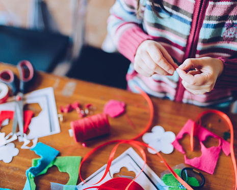 Sastre talleres de arte para niños - una niña cosiendo fieltro decoraciones photo