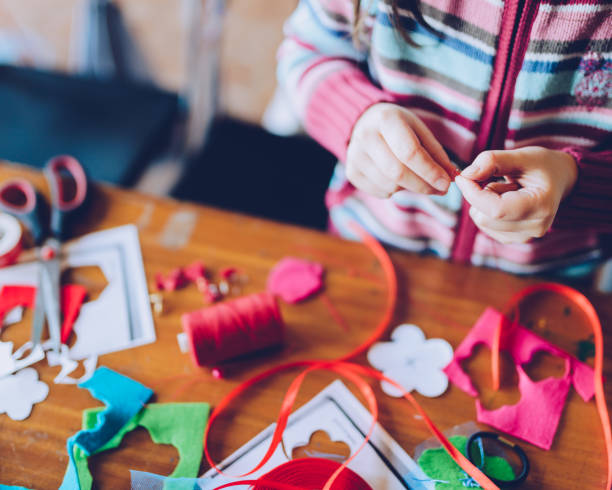 tailor art workshops for children - a girl sewing felt decorations tailor art workshops for children - a girl sewing felt decorations - colorful fabrics lying on a table craft stock pictures, royalty-free photos & images