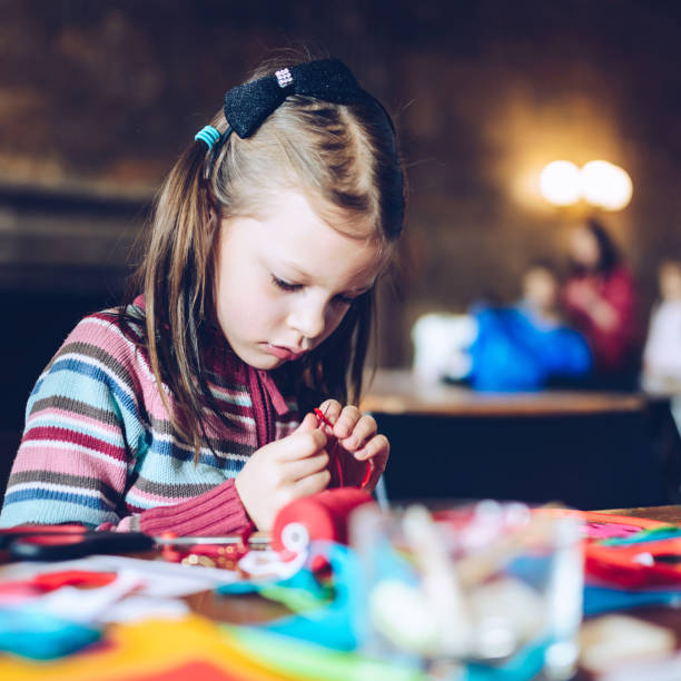 istock tailor art workshops for children - a girl sewing felt decorations 925854064