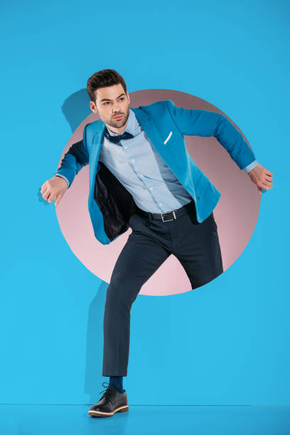 istock handsome man in fashionable clothes stepping through aperture on blue 925858400