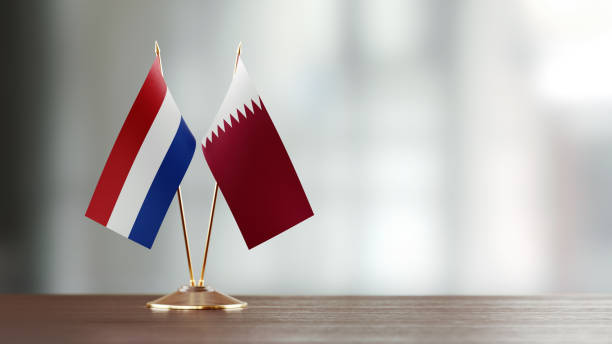 istock Qatari And Dutch Flag Pair On A Desk Over Defocused Background 925860572