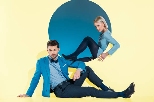 istock attractive stylish couple sitting and looking at camera on yellow 925863694