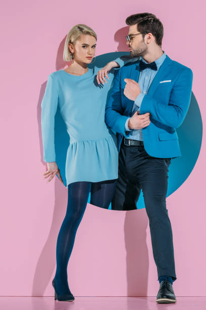 istock attractive stylish couple stepping through aperture on pink 925863832