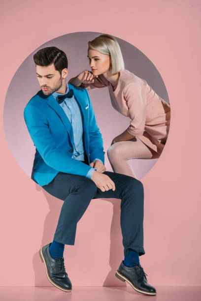 beautiful couple in stylish clothes looking down on pink