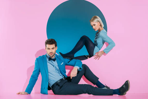 istock attractive stylish couple sitting and looking at camera on pink 925865572