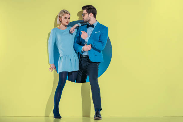 istock attractive stylish couple stepping through aperture on yellow 925865660