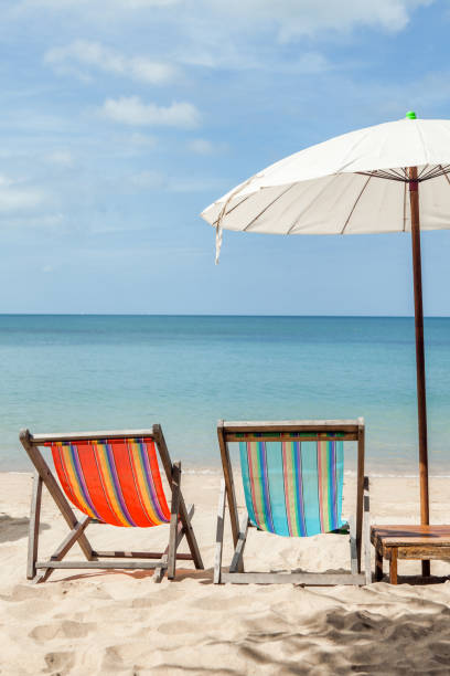 istock two beach lounge chairs under umbrella on beach. 925865810