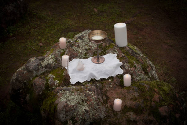 Altar on Rocks An altar with white candles, chalice, and quartz set up on a mossy rock near a forest. crystal chalice stock pictures, royalty-free photos & images