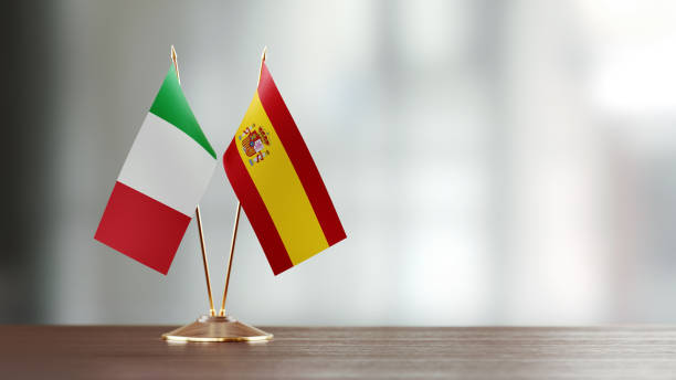 istock Italian And Spanish Flag Pair On A Desk Over Defocused Background 925873478