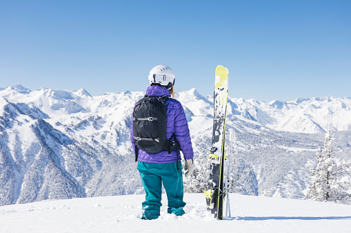 Woman with skis looking at the Pyrenees mountains