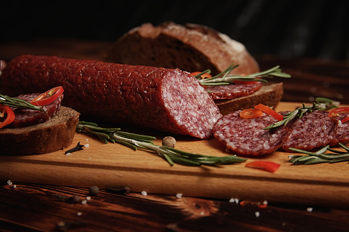 Smoked sausage on a wooden cutting board with a scattering of spices