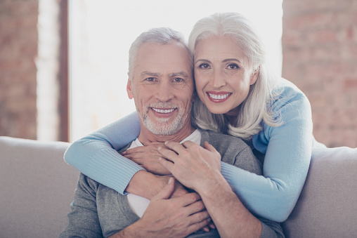 Close up portrait of two happy old married people, they are hugging and have perfect shiny white smiles