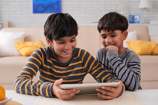 Two Indian excited brothers playing game on digital tablet