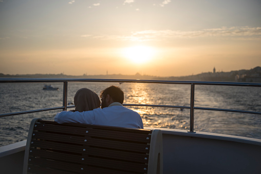 Istanbul, Turkey - November 8, 2017: A couple aboard a ferry crosses the Bosphorus Strait at sunset in Istanbul, Turkey