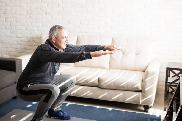 istock Mature man doing squats workout at home 925905698