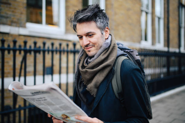 istock Young man reading newspapers in London downtown 925909002