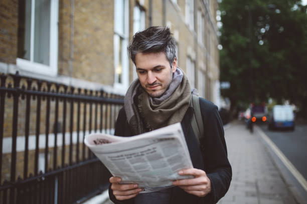 istock Young man reading newspapers in London downtown 925909294