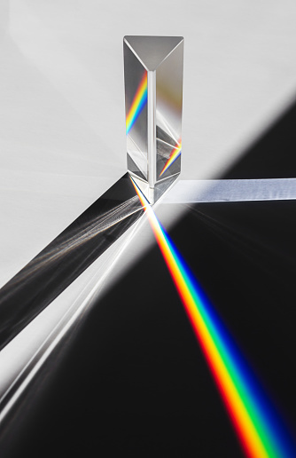 Un prisma de dispersión de luz del sol divide en un espectro sobre un fondo blanco photo