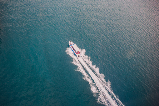 Top view of a white boat sailing in the blue sea