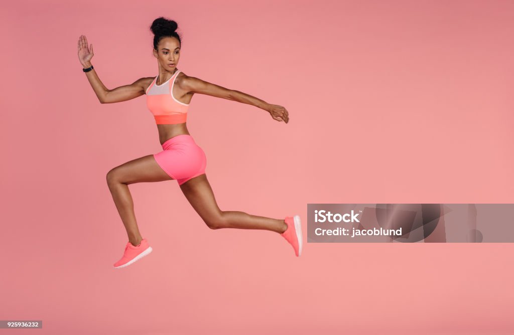 Healthy african woman sprinting on pink background Woman in sportswear running over pink background. Full length shot of healthy young african woman sprinting. Women Stock Photo