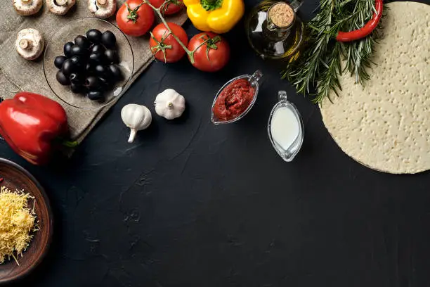 Photo of Pizza cooking ingredients. Dough, vegetables and spices. Top view with copy space