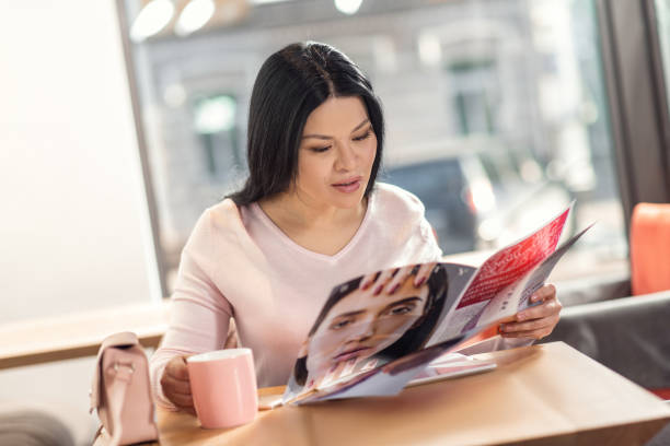 Cheerful delighted woman holding a magazine