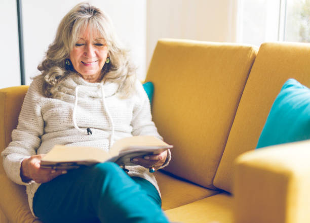 Senior woman reading in living room stock photo