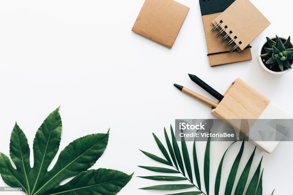 Minimal Office desk table with stationery set, supplies and palm leaves. Top view with copy space, creative flat lay. Desk Stock Photo