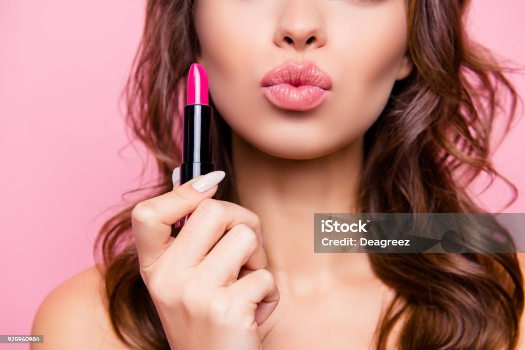 Beijo de ar para você. Close-up tiro recortado de femenino linda encantadora senhora adorável com incrível fazer cabelos ondulados, tubo de pomada rosa duro no braço. Mimos, conceito de correção de lábios - Foto de stock de Maquiagem royalty-free