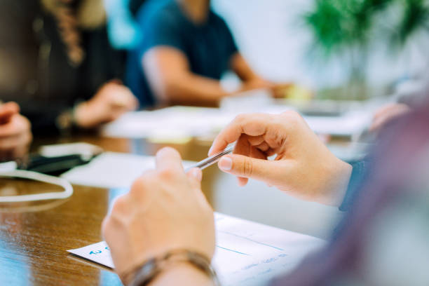 istock businessman holding pen while discussing with colleagues at conference table in creative office 925963200