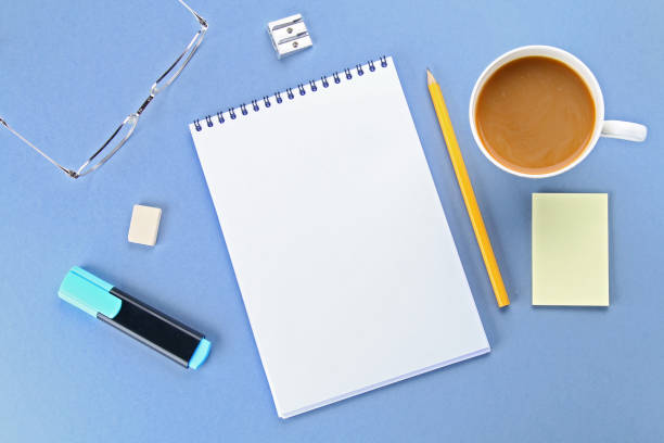 istock Top view image of open notebook with blank pages and coffee on blue background, ready for adding or mock up. Still life, business, office supplies or education concept. 925965890