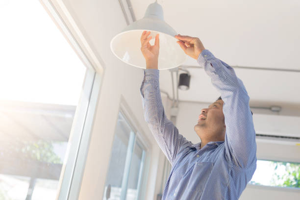 istock Asian man changing light bulb in coffee shop , installing a fluorescent light bulb 925977550