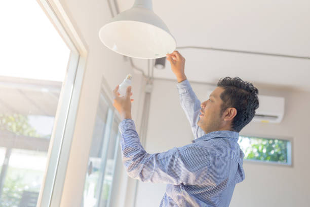 homem asiático trocar lâmpada na cafeteria, instalar uma lâmpada fluorescente - changing lightbulb - fotografias e filmes do acervo