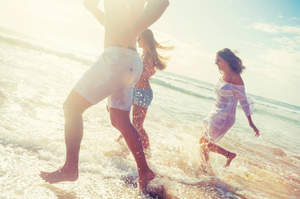 istock Smiling young people running on the beach in the sun. 925980094