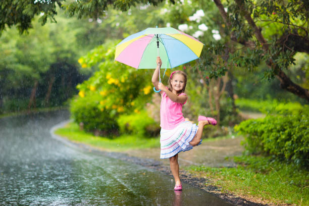 istock Kid with umbrella playing in summer rain. 925987396
