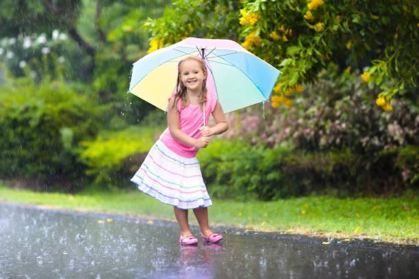 istock Kid with umbrella playing in summer rain. 925989464