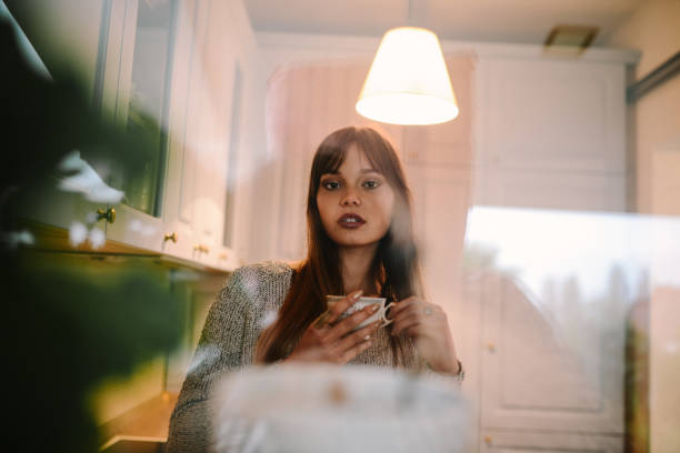 istock Cute Female in Kitchen Drinking Coffee and Looking through Window 925998356
