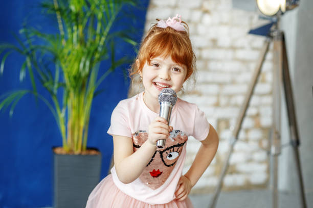 istock Smiling child sings a song into the microphone. The concept is c 926015956