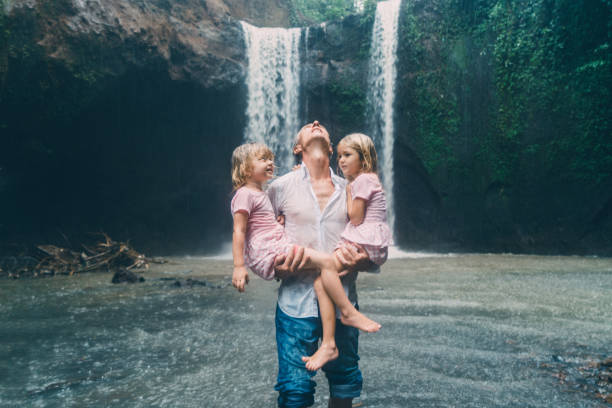 istock Father holding two daughters near Tibumana waterfall  in Bali 926023018