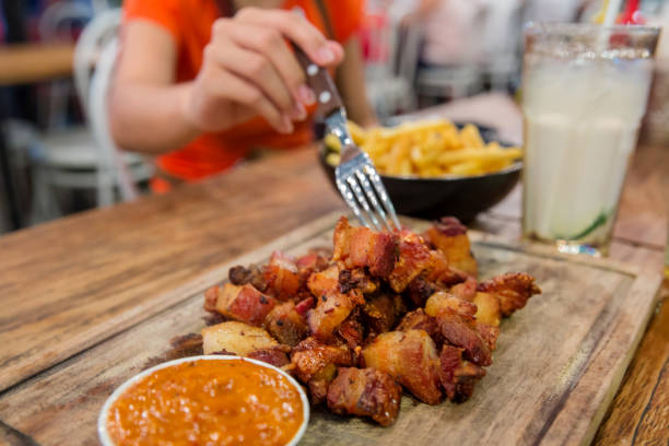 women eating crispy roast pork belly - non alcoholic beverage comfort food snack dining table imagens e fotografias de stock