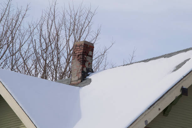 Red brick chimney with iron chimney cap on the roof in snow.