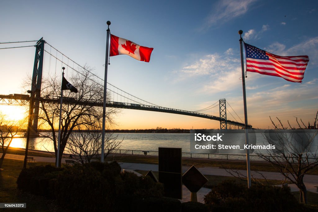 Ambassador Bridge with Flags The Ambassador Bridge links Detroit, Michigan, USA with Windsor, Ontario, Canada.  It is one of the busiest trade routes in North America.  This photo depicts the bridge, as seen from Windsor.   The national flags of the USA and of Canada are notable in the foreground. Canada Stock Photo