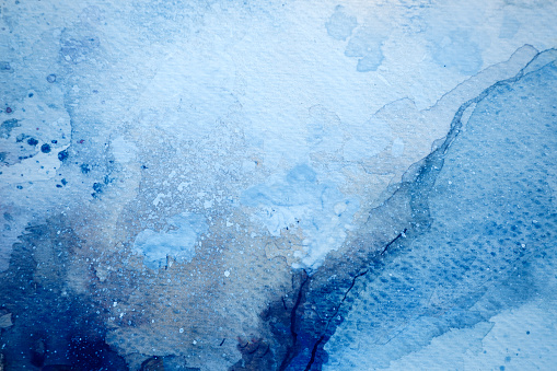 Abstract wet blue watercolor background on white watercolor paper. My own work.