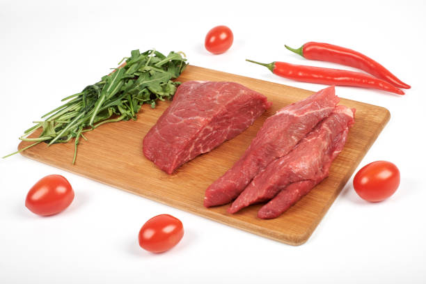 istock Sliced raw beef on cutting board and vegetables isolated on white background 926047216