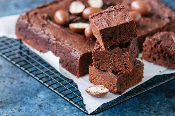 istock Dark chocolate brownie square on a wire rack decorated with creamy chocolate eggs. Blue stone background. 926058902