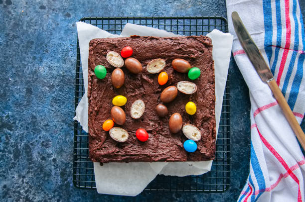 istock Dark chocolate brownie square on a wire rack decorated with creamy chocolate eggs. Blue stone background. 926058916