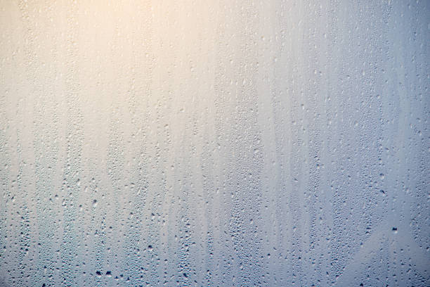 Morning sunrise through the raindrops on the glass. Condensation on Windows in the cold. Texture of the water stock photo