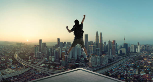 junger mann springt auf dach - skyscraper city life urban scene building exterior stock-fotos und bilder