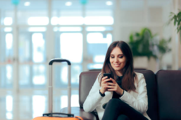 woman reading phone messages in airport waiting room - business travel people traveling airport journey imagens e fotografias de stock