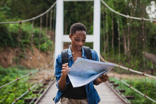 afroamerikanische frau, blick auf eine karte reisen und erkunden sie konzept - people tourism tourist travel destinations stock-fotos und bilder